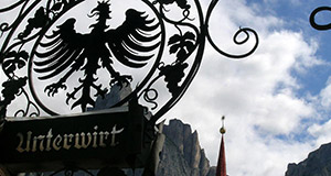 Coat of arms of the Unterwirt now Hotel Schwarzer Adler with the Sciliar mountain in the background