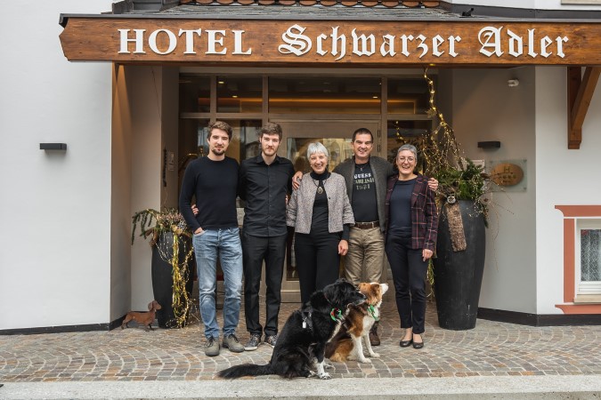 The Mutschlechner family with their dogs in front of the entrance to the Hotel Schwarzer Adler